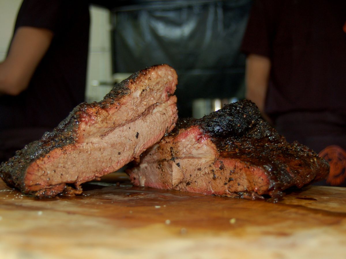 Two pieces of smoked brisket on a wooden cutting board