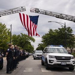 Officers salute outside the Cook County medical examiner’s office as an ambulance passes, containing the body of a high-ranking Chicago Police officer who died of an apparent suicide, Tuesday afternoon, July 28, 2020.