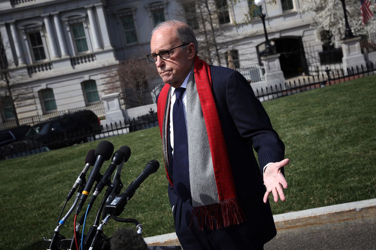 Larry Kudlow wearing a red scarf speaking into multiple microphones on the White House lawn.