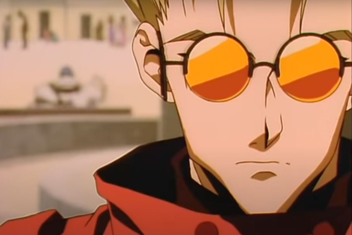 A man with round tinted glasses looks ahead in Trigun.