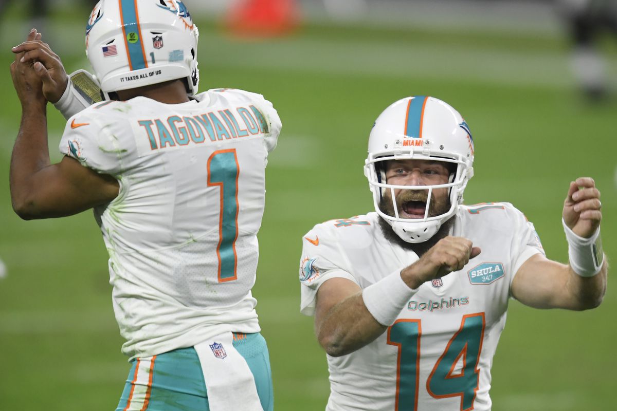 Ryan Fitzpatrick #14 of the Miami Dolphins celebrates his touchdown pass with Tua Tagovailoa #1, to take a 23-22 lead over the Las Vegas Raiders, during the fourth quarter at Allegiant Stadium on December 26, 2020 in Las Vegas, Nevada.