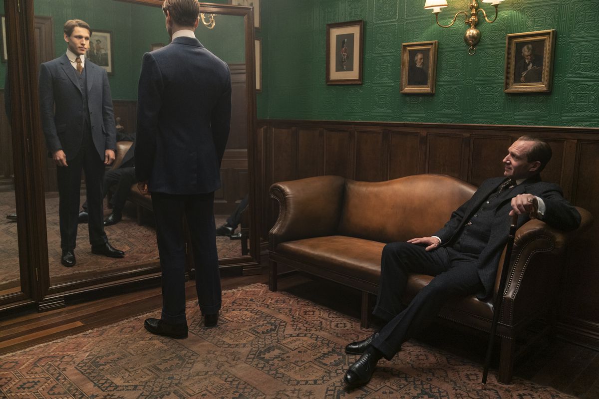 Orlando Oxford (Ralph Fiennes) sits while Conrad (Harris Dickinson) tries on his Kingsman suit