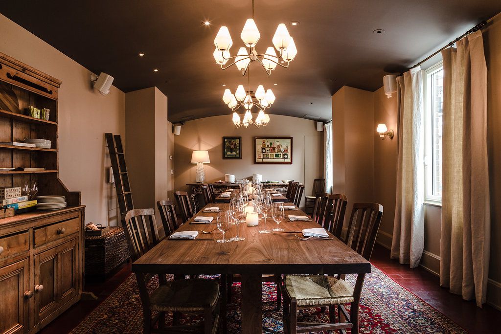 a room with a long wooden dining table and a lit chandelier 