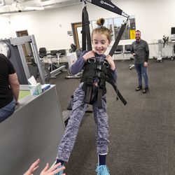 Nora Booth, 6, uses a body weight support system as she works with pediatric physical therapists Rick Reigle, top, and Ashlyn Rittmanic at Neuroworx in Sandy on Friday, March 8, 2019. Booth, who has been diagnosed with acute flaccid myelitis, has therapy at Neuroworx several times a week. Acute flaccid myelitis affects an area of the spinal cord called gray matter, which can cause the muscles and reflexes in the body to become weak.