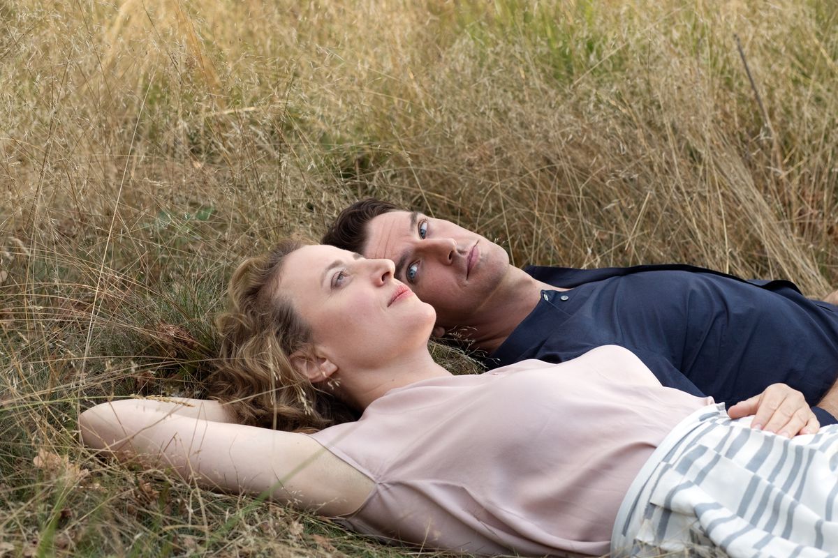 Maren Eggert and Dan Stevens lie in the grass together in I’m Your Man