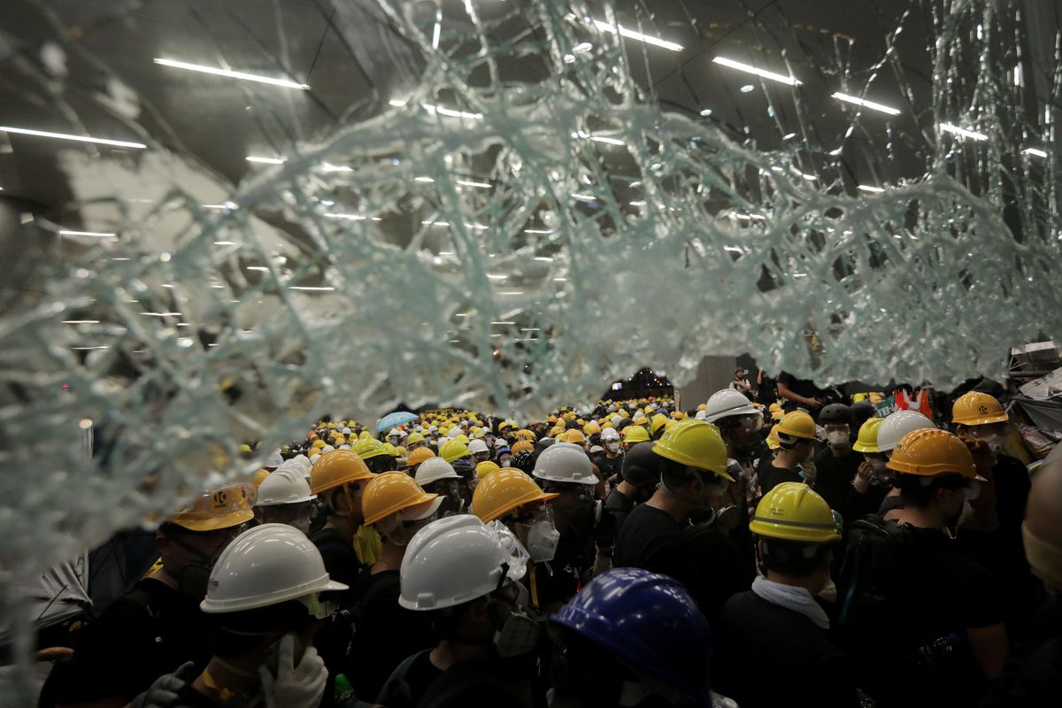 Protesters outside the Hong Kong legislative building on July 1, 2019, framed by smashed glass.