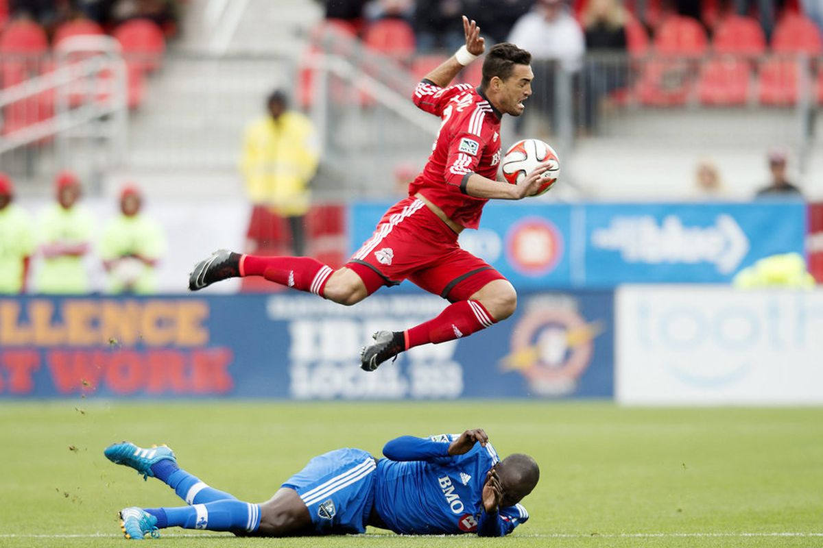 Toronto FC's Gilberto, top, leaps over Montreal Impact's Hassoun Camara after being tackled. (AP Photo/The Canadian Press, Darren Calabrese)