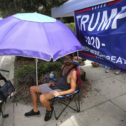 Ray Renaud, from Daytona Beach, Fla., is ready with a beach umbrella as supporters of President Donald Trump camp out in front of the Amway Center, Monday, June 17, 2019, ahead of Tuesday's 2020 campaign kick-off rally in Orlando, Fla. (Joe Burbank/Orlando Sentinel via AP)