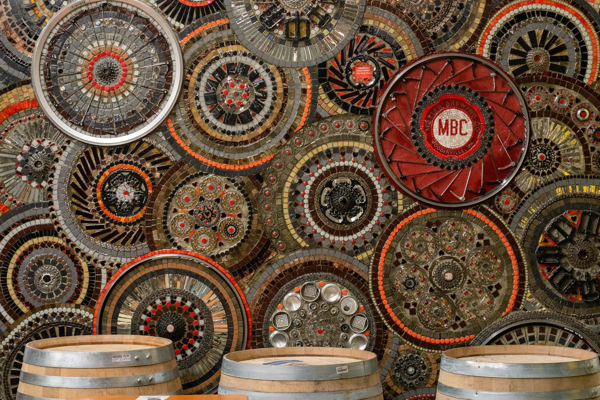 A few oak casks with a mosaic of a bunch of circular shapes with red, orange, black, and grey tile.