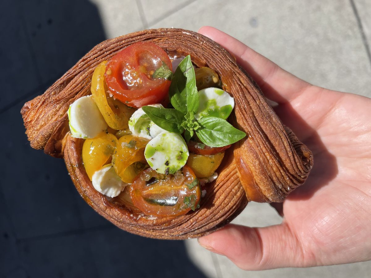 A savory croissant from Butter &amp; Crumble packed with cherry tomatoes, circles of mozzarella, and a sprig of basil