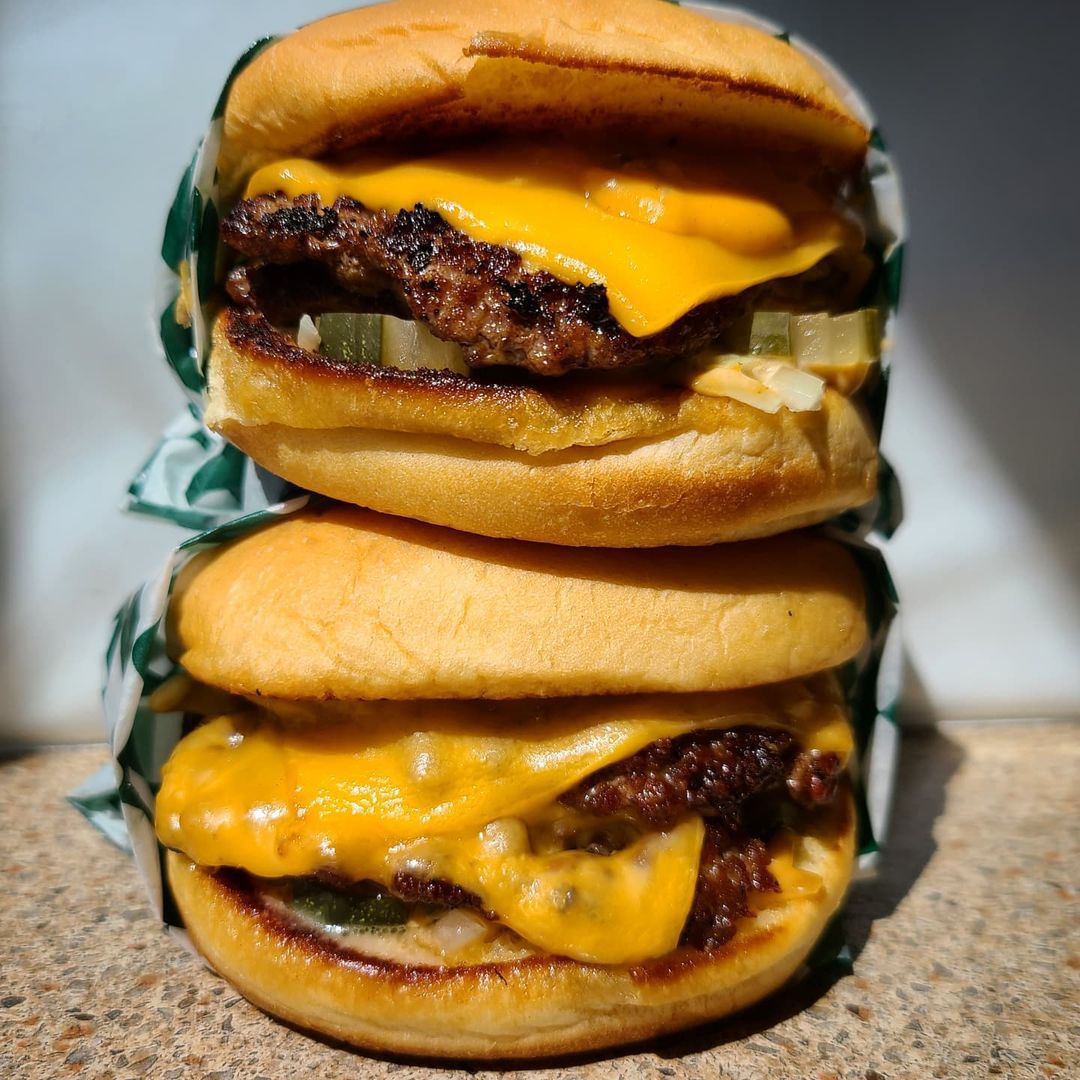 two cheeseburgers sitting on top of each other.