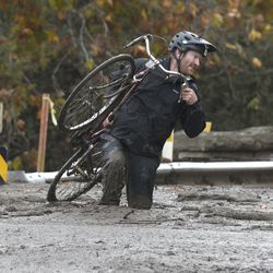 Carpinteria resident Jeff Gallup carries his bike through mud on Foothill Road in Carpinteria, Calif., Tuesday, Jan. 9, 2018. (AP Photo/Michael Owen Baker)