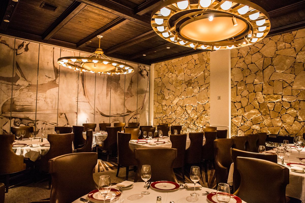 A dramatic restaurant interior with chandeliers and chocolate brown chairs