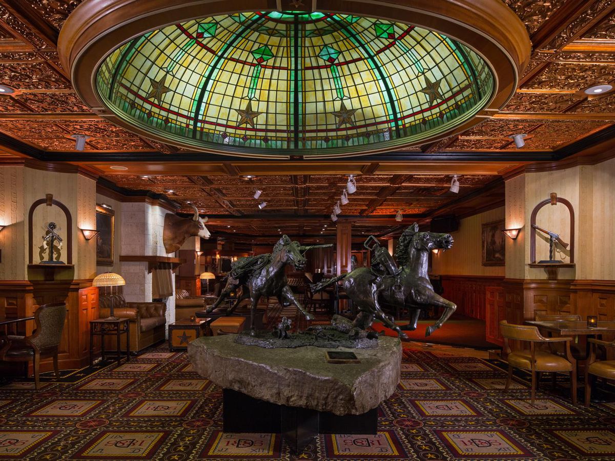 An elegant bar with a statue of a horse in the middle and a domed stained glass above it.