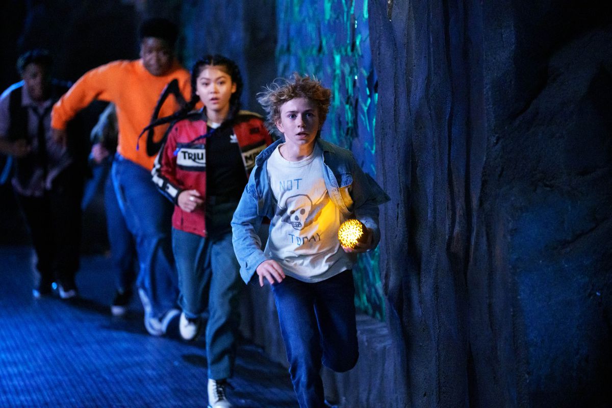 charlie, a blonde kid, leading a group of children through a dark hallway