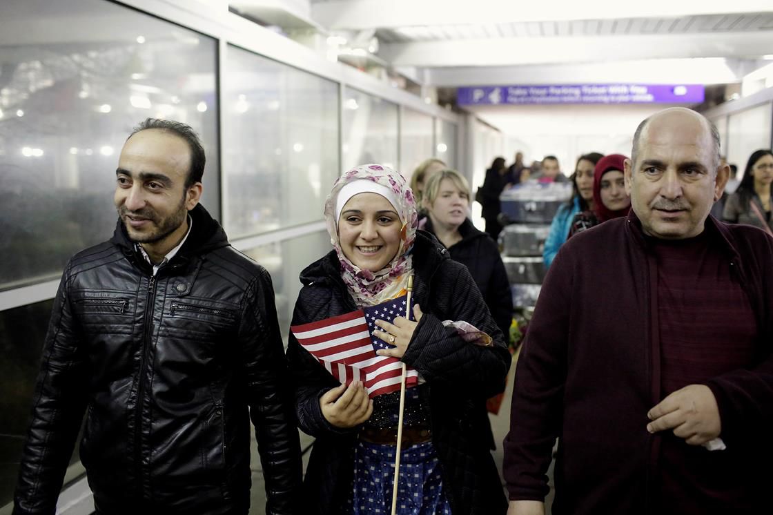 Syrian refugee Baraa Haj Khalaf holds the American flag as she walks with her husband Abdulmajeed and father Khaled Haj Khalaf as she leaves O'Hare International Airport on February 7