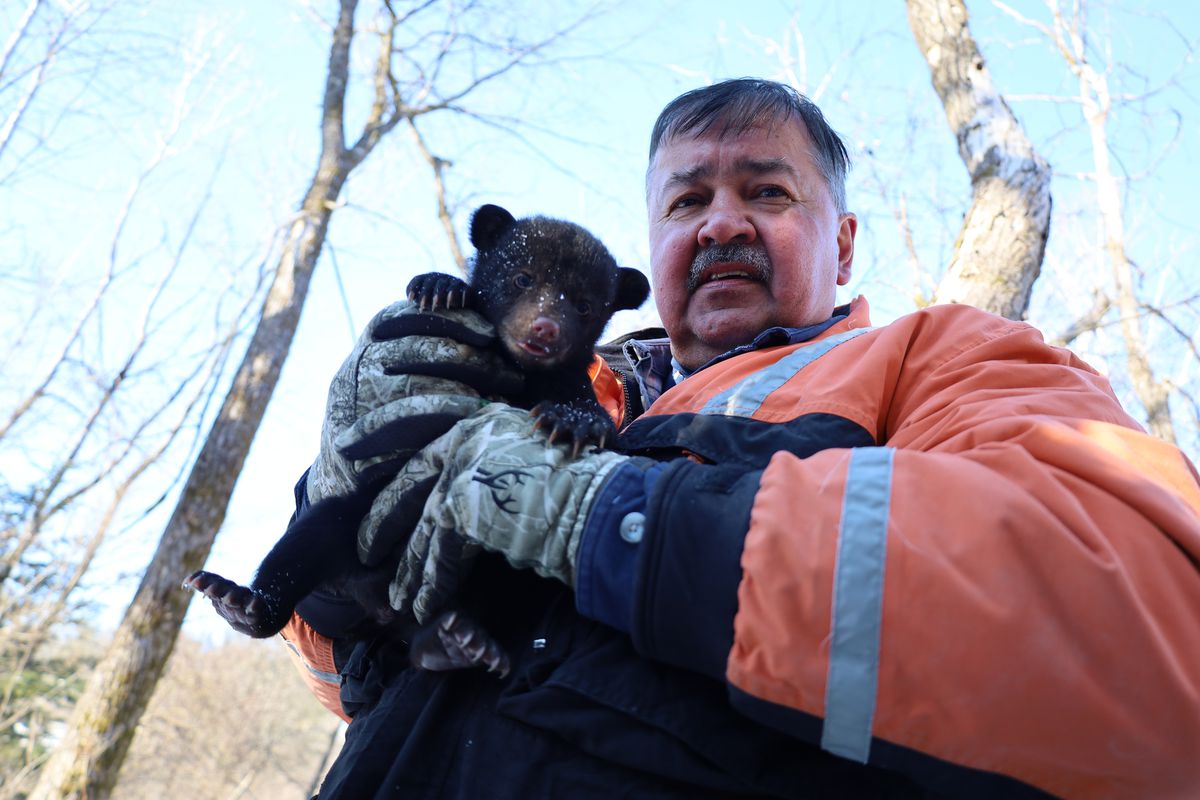Don Reiter tiene in braccio un piccolo cucciolo di orso.