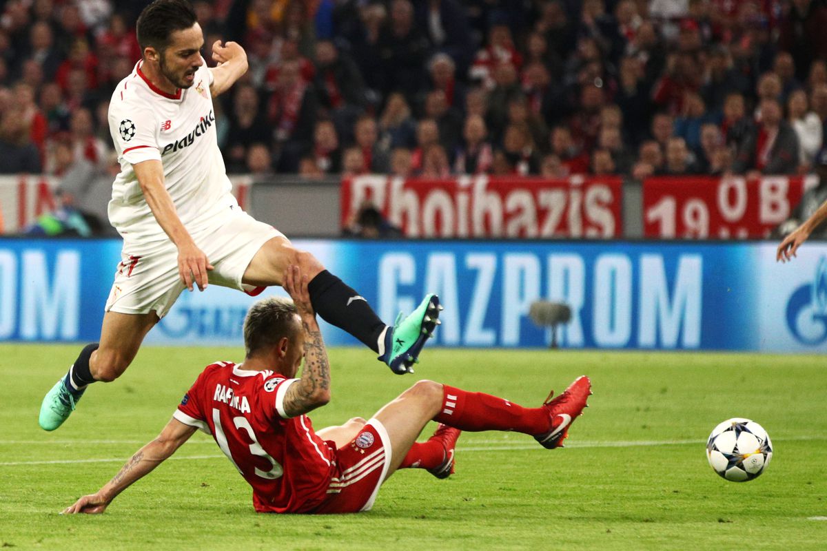 MUNICH, GERMANY - APRIL 11: Rafinha of Bayern Muenchen grabs hold of Pablo Sarabia of Sevilla in the moments preceeding his injury during the UEFA Champions League Quarter Final Second Leg match between Bayern Muenchen and Sevilla FC at Allianz Arena on April 11, 2018 in Munich, Germany.