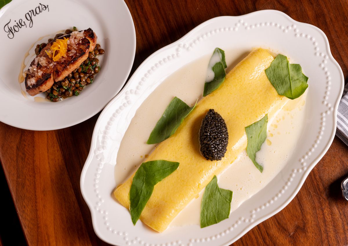 A dollop of caviar on an omelet surrounded by a white sauce and sorrel leaves. 