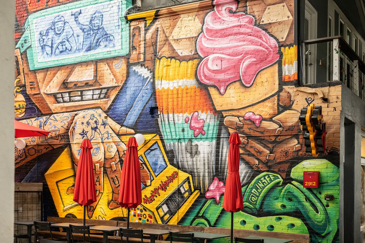 A colorful mural depicting a robot holding a burger truck at Heavy Handed.