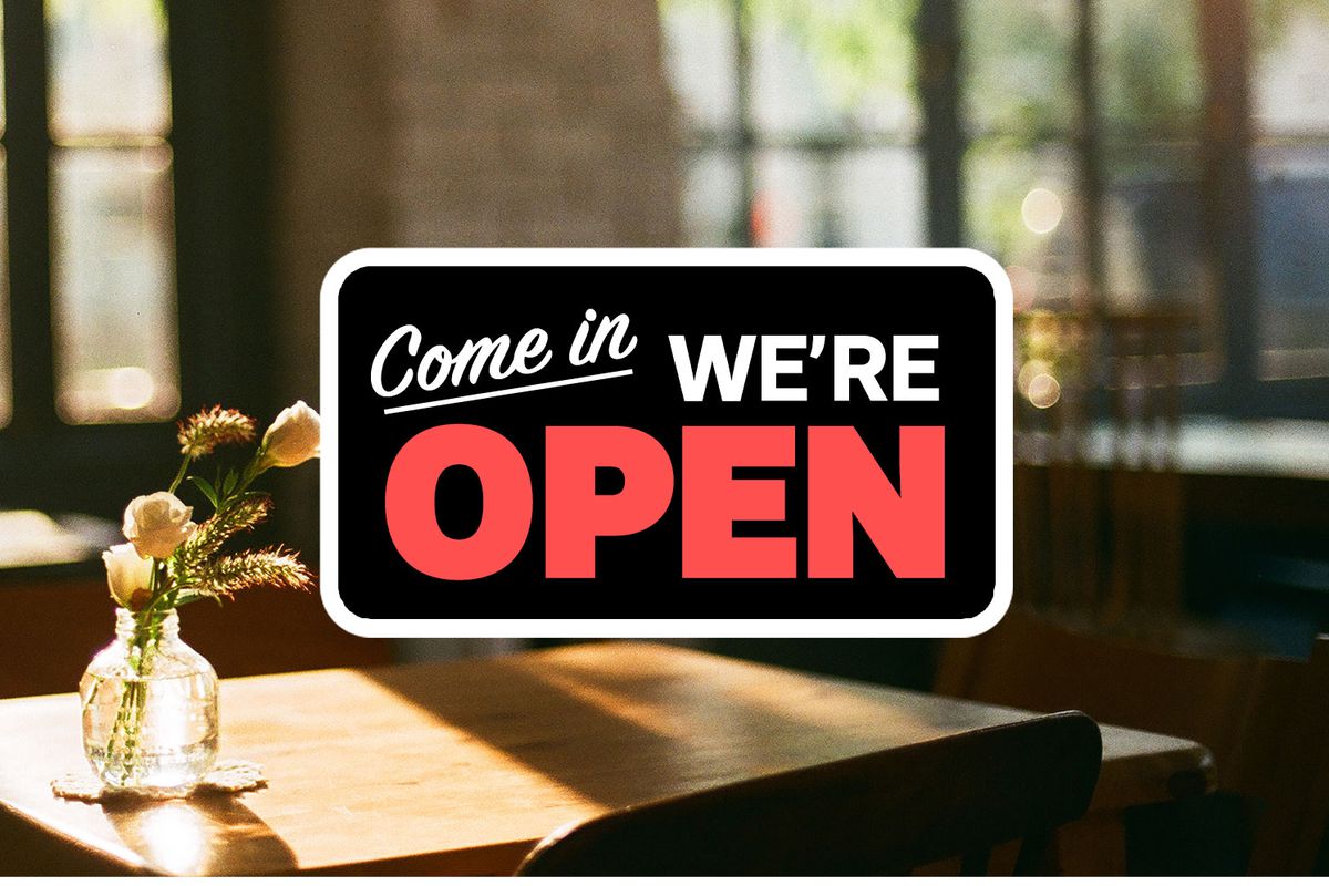 In the window of a restaurant, a sign reads: “Come In, We’re Open.”