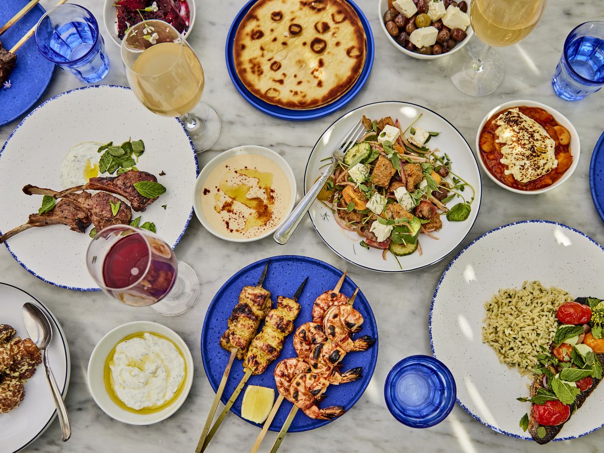 An overhead shot of Greek food on blue plates and a marble tabletop.