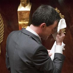 French Prime Minister Manuel Valls wipes his brow after delivering a speech prior to a parliamentary vote of confidence over the government's economic reform at the French National Assembly, Paris, Thursday, Feb 19, 2015. Valls faced a parliamentary showdown Thursday with the fate of his government in the balance — as rebels within his own Socialist Party teamed up with conservatives to demand he scrap pro-business policies he rammed through Parliament without a vote. 