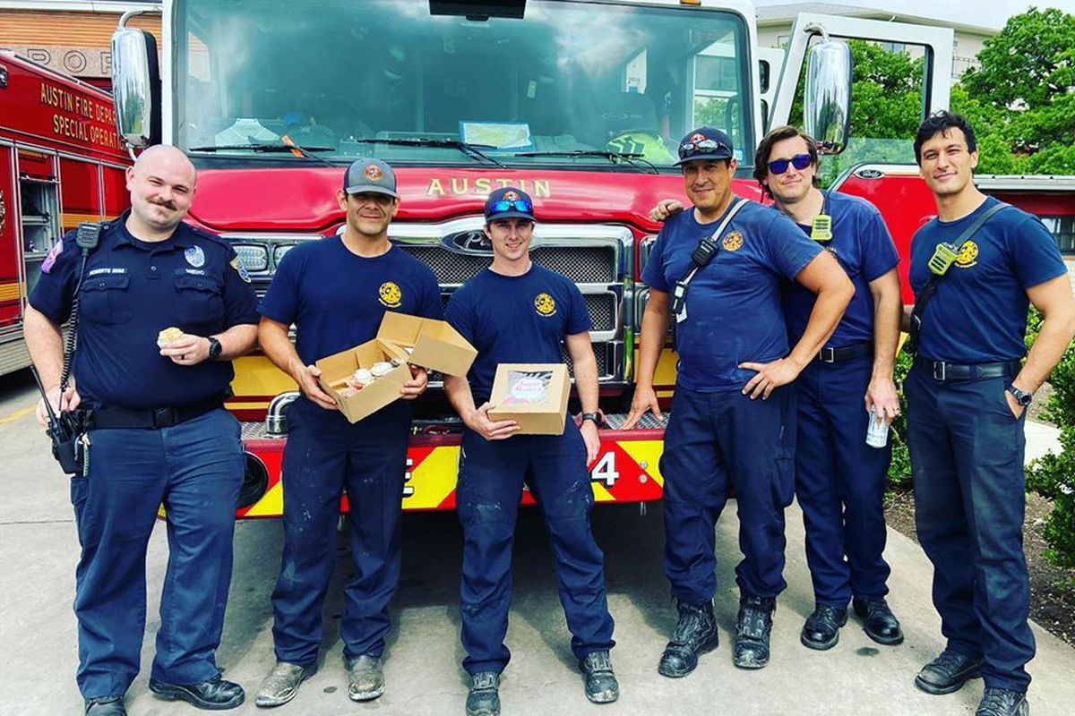 Five firefighters in uniform holding boxes of cupcakes from Sugar Mama’s in front of a red fire truck