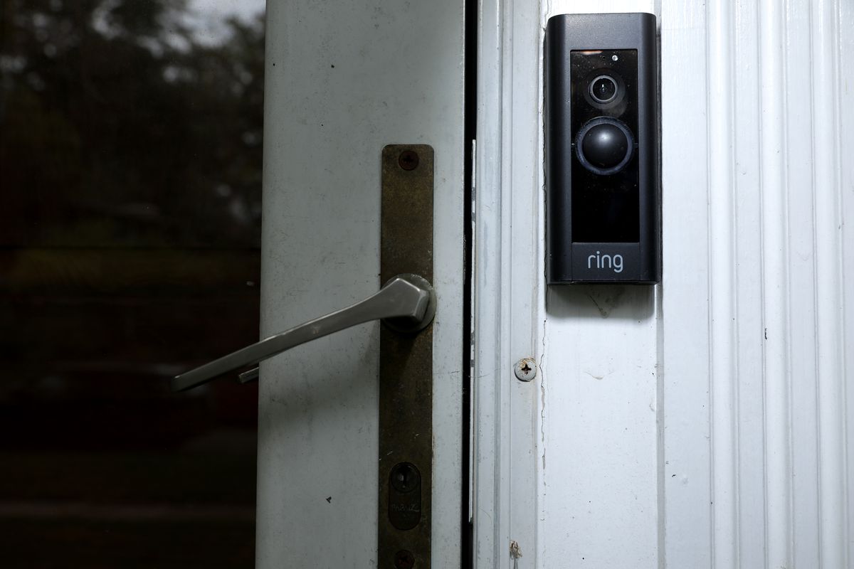 Image of an Amazon Ring doorbell camera mounted beside the handle of a house’s front door.