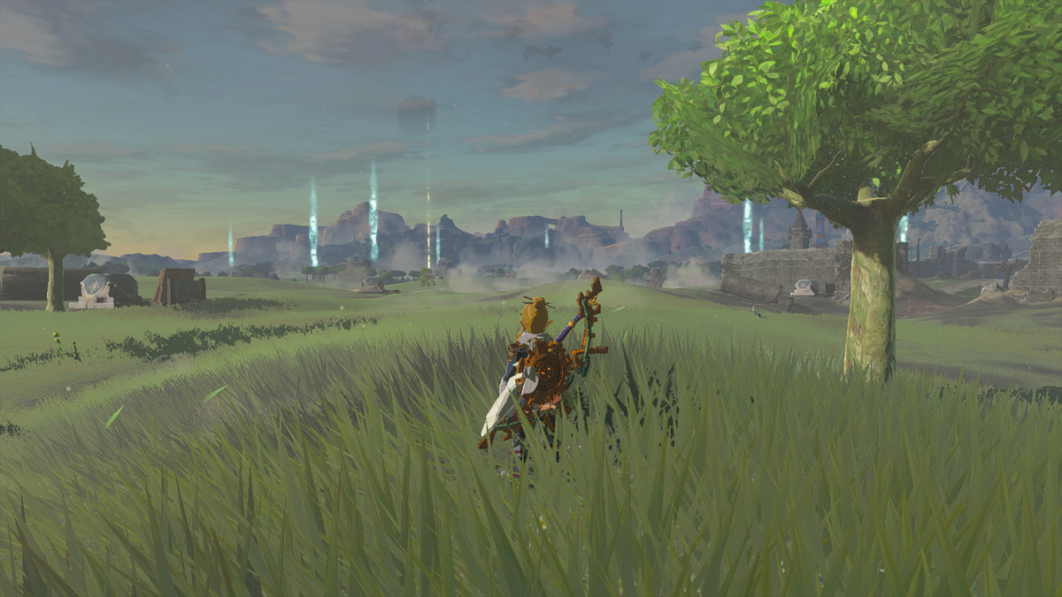 An image of Link standing in a field in The Legend of Zelda: Tears of the Kingdom. Distant pillars of light mark the entrances to caves. 
