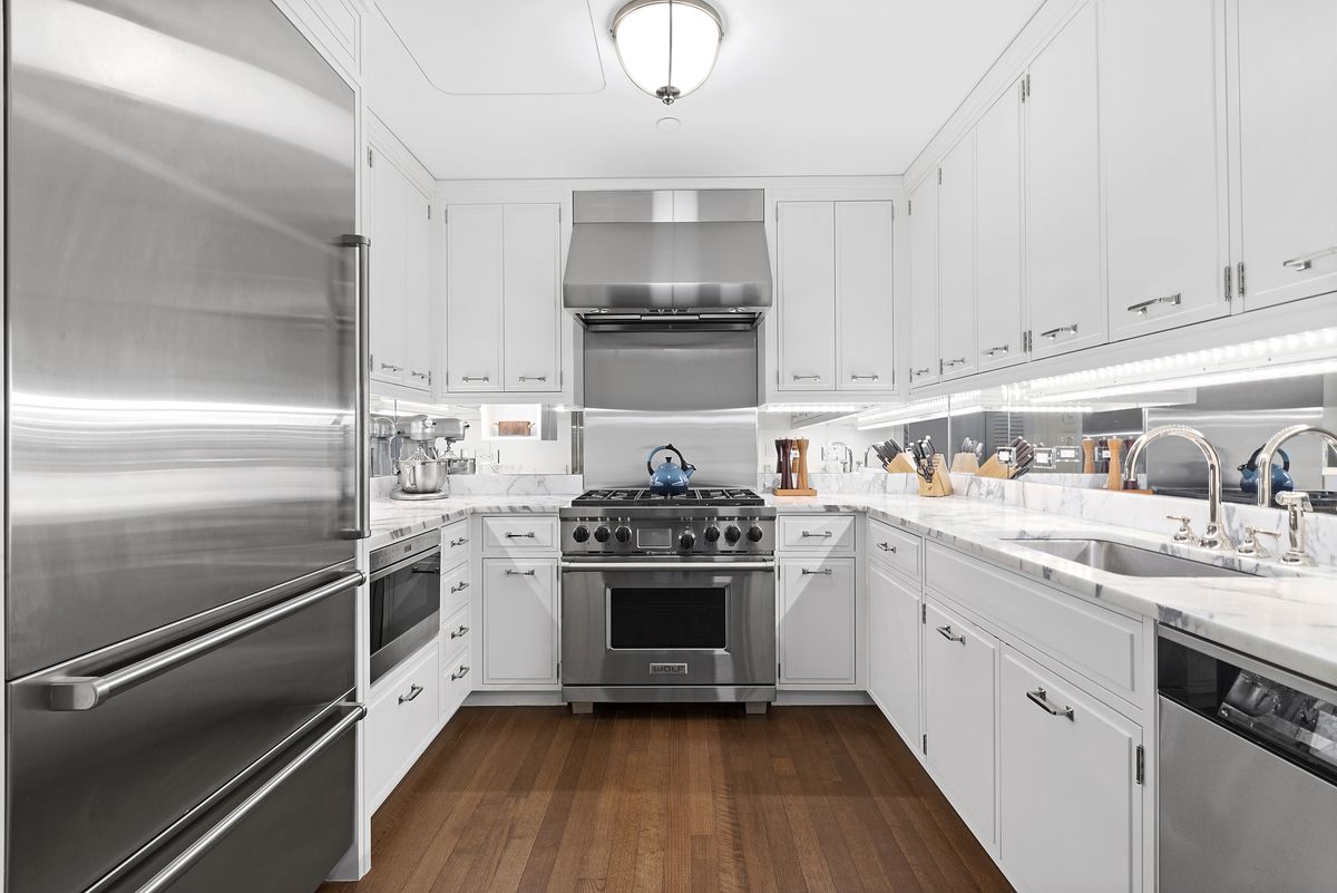 A kitchen with white cabinetry and hardwood floors.