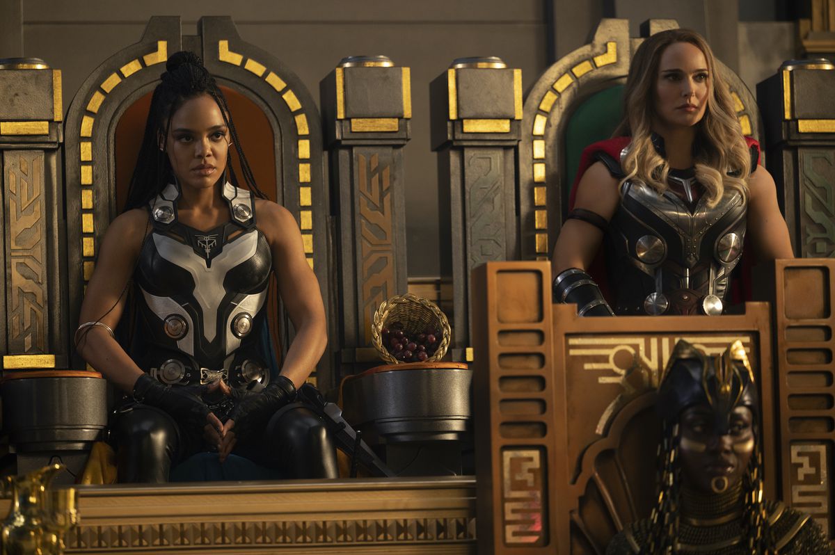 Tessa Thompson as Valkyrie and Natalie Portman as Jane Foster sit on throne-like chairs in Omnipotence City in Thor: Love and Thunder