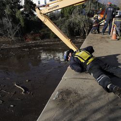 An emergency worker looks down from an overpass toward a flooded area of Highway 101 in Montecito, Calif., Thursday, Jan. 11, 2018. Rescue workers slogged through knee-deep ooze and used long poles to probe for bodies Thursday as the search dragged on for victims of the mudslides that slammed this wealthy coastal town. (AP Photo/Marcio Jose Sanchez)