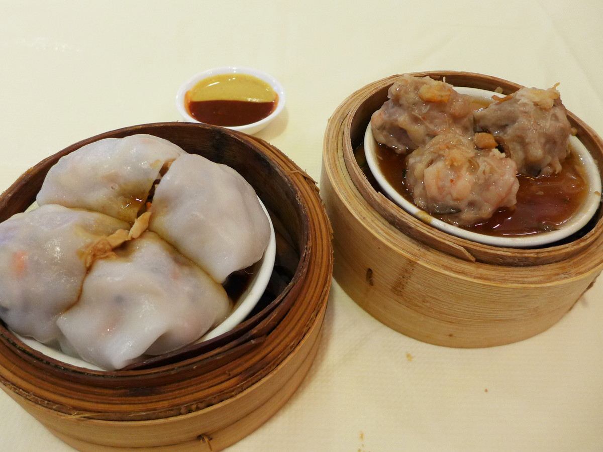 Two dim sum dishes — bundles covered in a thin white wrapper and minced beef balls — stand next to a dipping sauce.