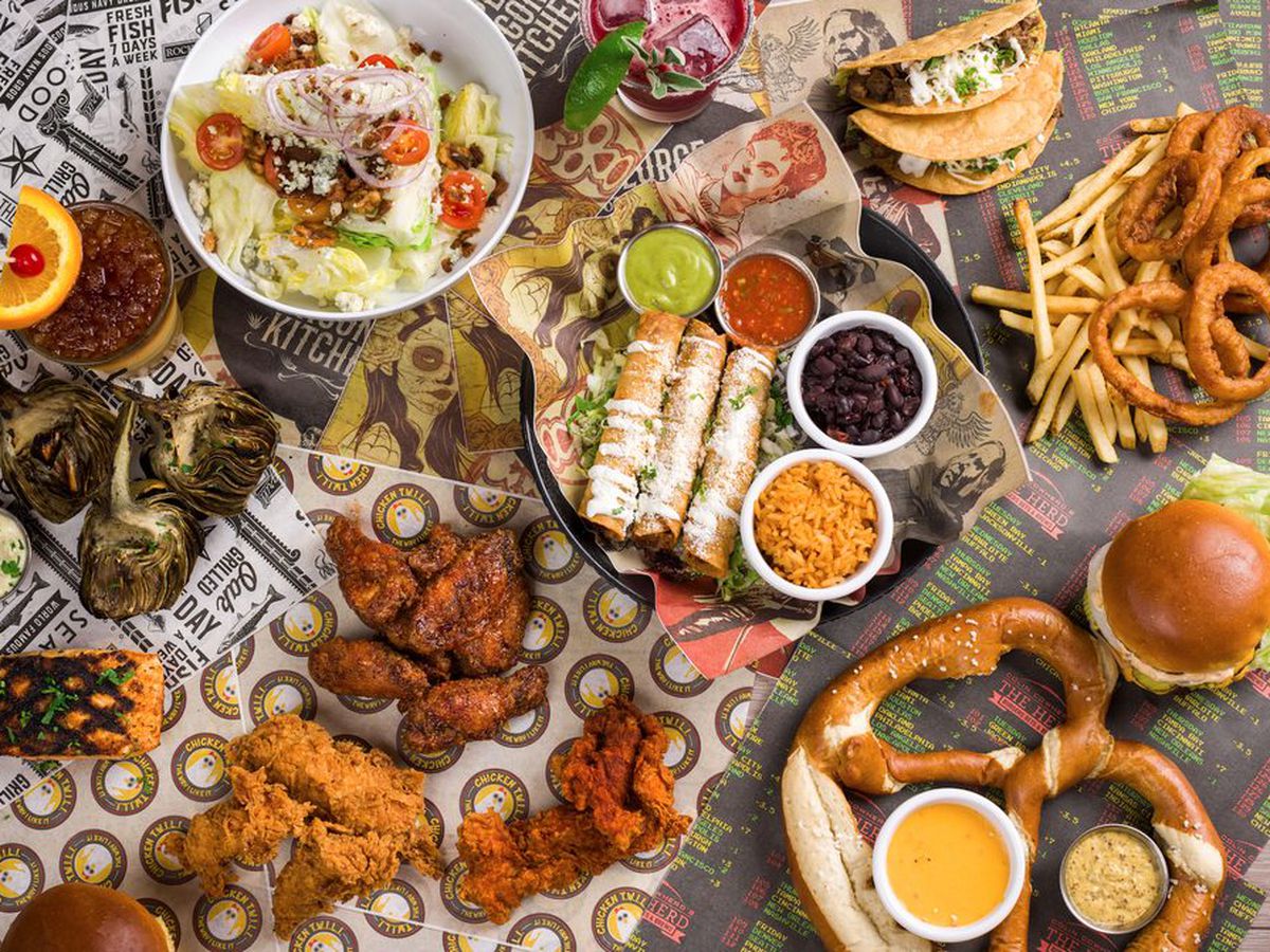 An overhead shot of fried foods on paper at a sports bar.