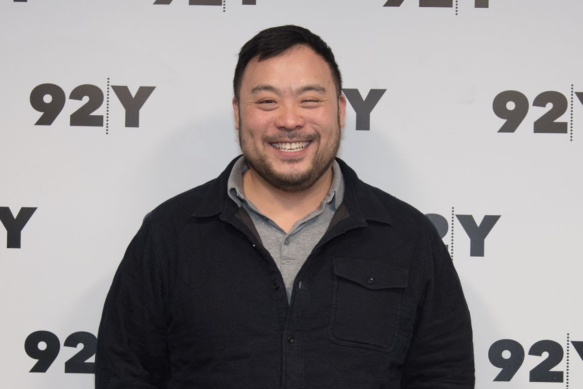 A smiling David Chang standing in front of a 92Y backdrop.