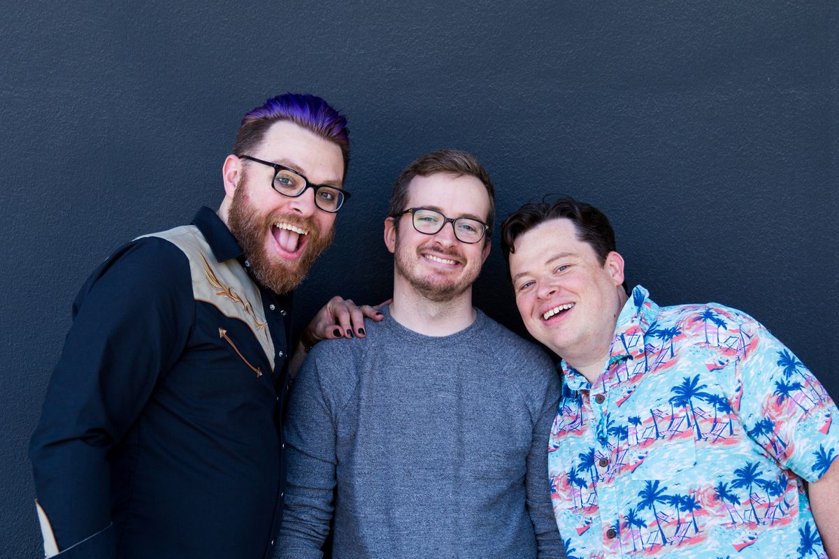 Travis, Griffin, and Justin Mcelroy standing against a blue background.