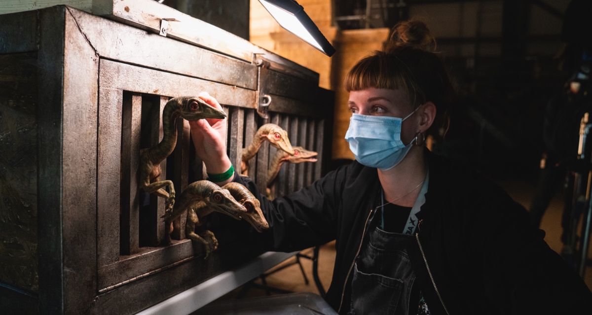 A woman in a surgical mask tends a cage full of tiny dinos in Jurassic World: Dominion
