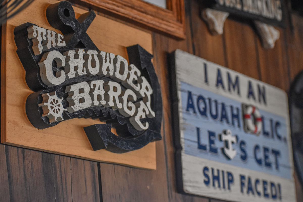 A wooden carved sign for a restaurant advertising chowder, with an anchor image.