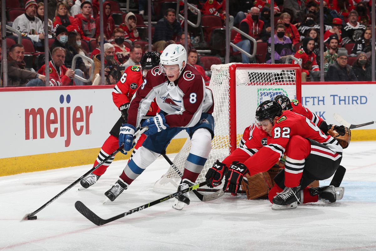 Cale Makar #8 of the Colorado Avalanche and Caleb Jones #82 of the Chicago Blackhawks reach for the puck in the third period at United Center on January 04, 2022 in Chicago, Illinois.