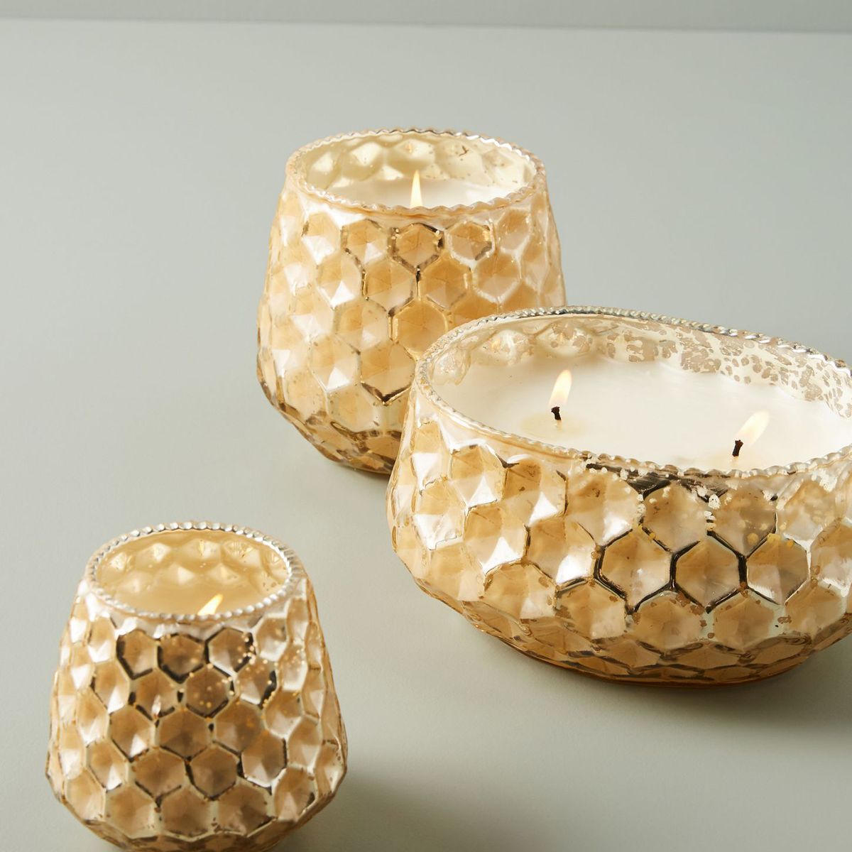 Three candles of different sizes with a honeycomb pattern on the container.