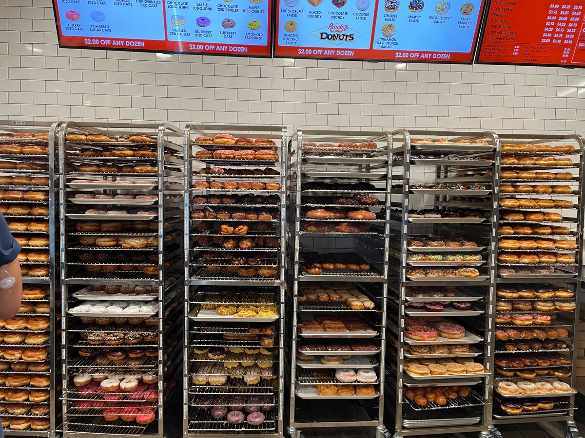 Five bakery racks full of fresh doughnuts
