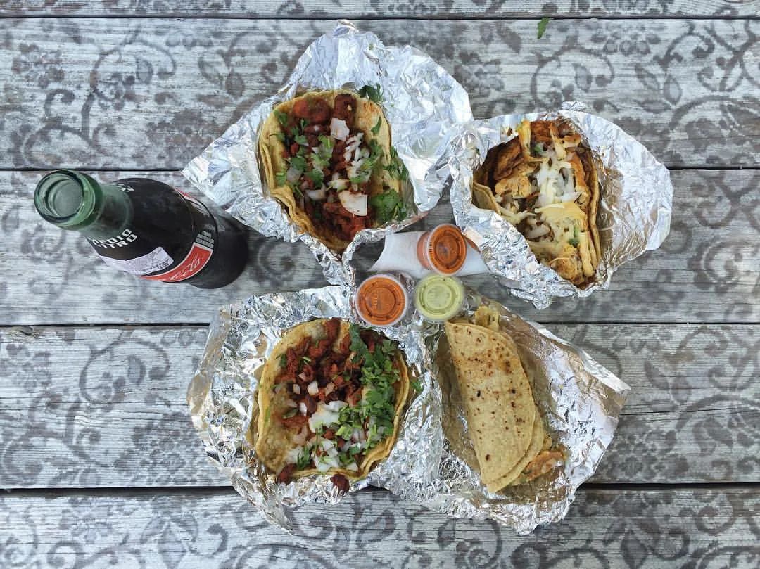 Four tacos spread out in foils.
