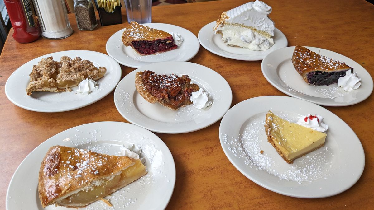 Seven pies on plates on a diner table.