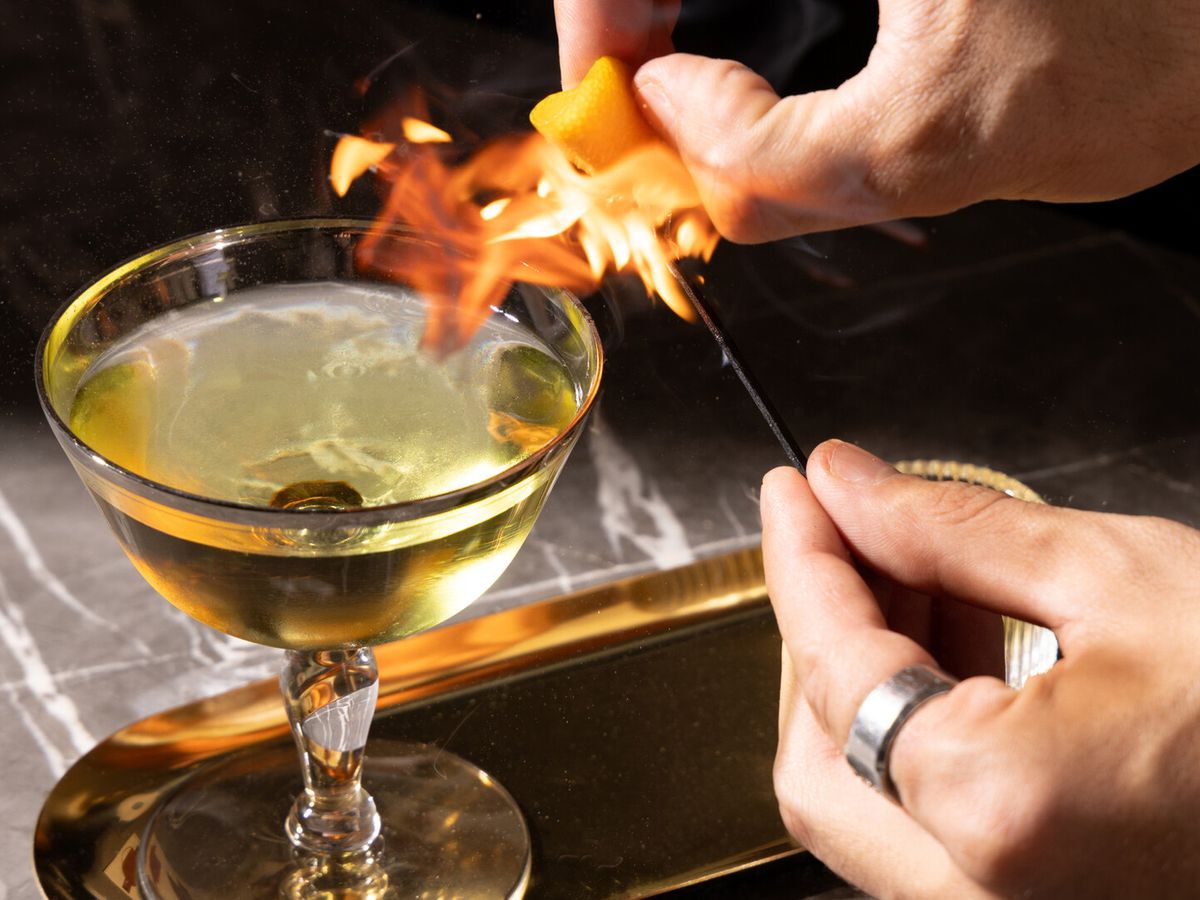 A cocktail with a garnish that is set aflame. 