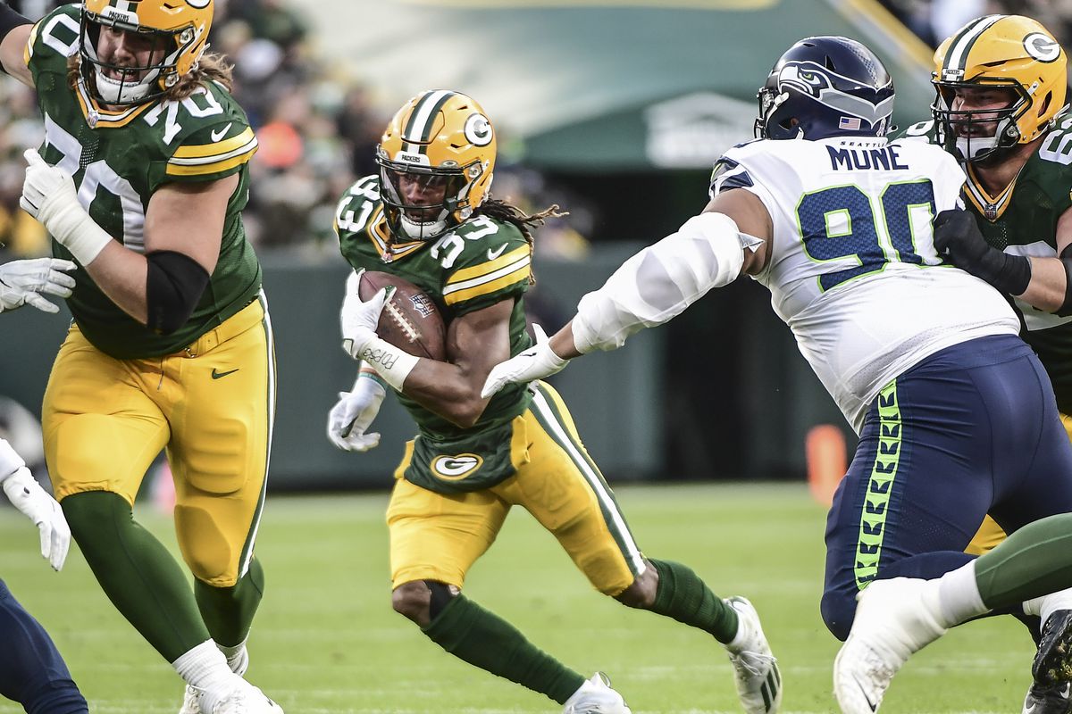 Green Bay Packers running back Aaron Jones (33) tries to avoid a tackle by Seattle Seahawks defensive tackle Bryan Mone (90) in the first quarter at Lambeau Field.
