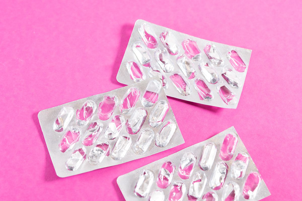 Empty blister packs sit on a pink background.