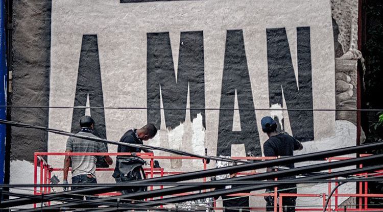 Jared Diaz (from left), Darius Dennis, Robin Alcantara (hidden) and Ephraim Gebre work on the lettering of the “I AM A MAN” mural in Wicker Park.