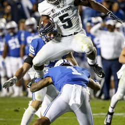 Utah State Aggies wide receiver Ron'quavion Tarver (1) hurdles Brigham Young Cougars defensive back Troy Warner (1) as he runs up the middle during the Utah State versus BYU football game at LaVell Edwards Stadium in Provo on Friday, Oct. 5, 2018.