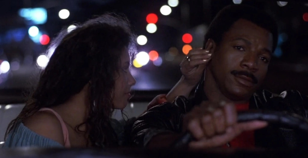 Carl Weathers drive while Vanity touches his face in Action Jackson